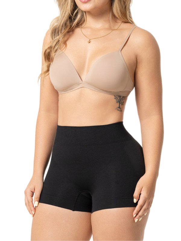 Woman wearing a beige bra and black high-waisted shorts on a white background