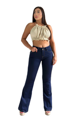 Woman wearing a beige top and blue jeans standing in a living room.