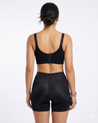 Person wearing a black sports bra and shorts on a white background