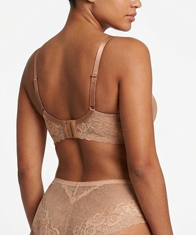 Woman wearing a beige lace bra and panties set on a plain background