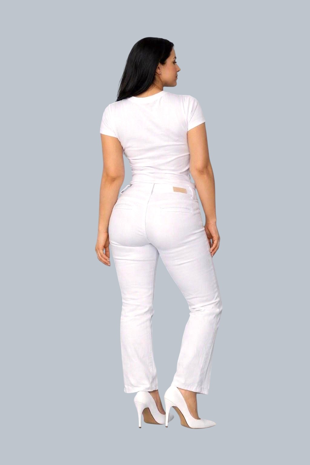 Stella's Corset high-waisted white sculpting denim pants worn by a woman with white heels against a blurred background