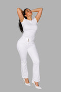Model wearing Stella's Corset high-waisted white sculpting denim pants with a triple-button closure and white heels.