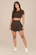 Stella's Corset olive green athletic skirt worn by a model with a matching crop top and white sneakers.